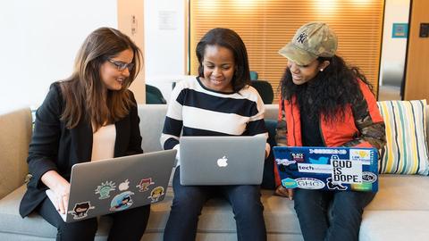 Three students sitting together with laptops