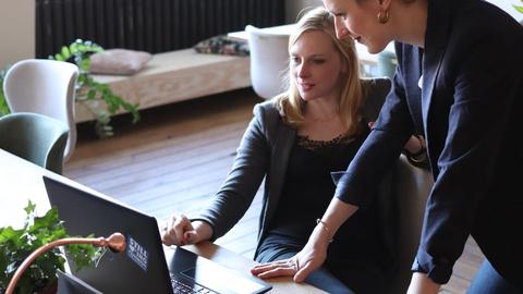 Two women at an office looking at a computer monitor