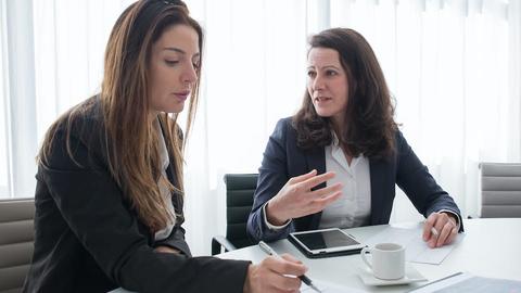 Two women sitting at a conference table talking