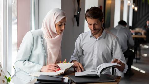 A woman and a man looking at two books