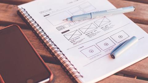 a notepad with a drawing of a webpage interface wireframe