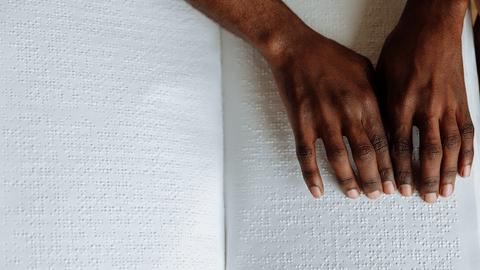 A person using their hands to read a Braille book