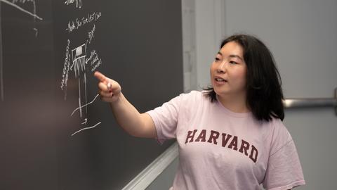 A student points to a chalkboard diagram.