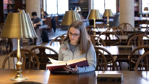 Student reading a large print format book at a Harvard Library.