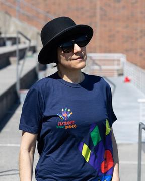 Someone wearing a black hat and sunglasses looking into the distance