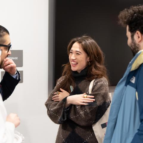 Four people stand in a circle talking and laughing.