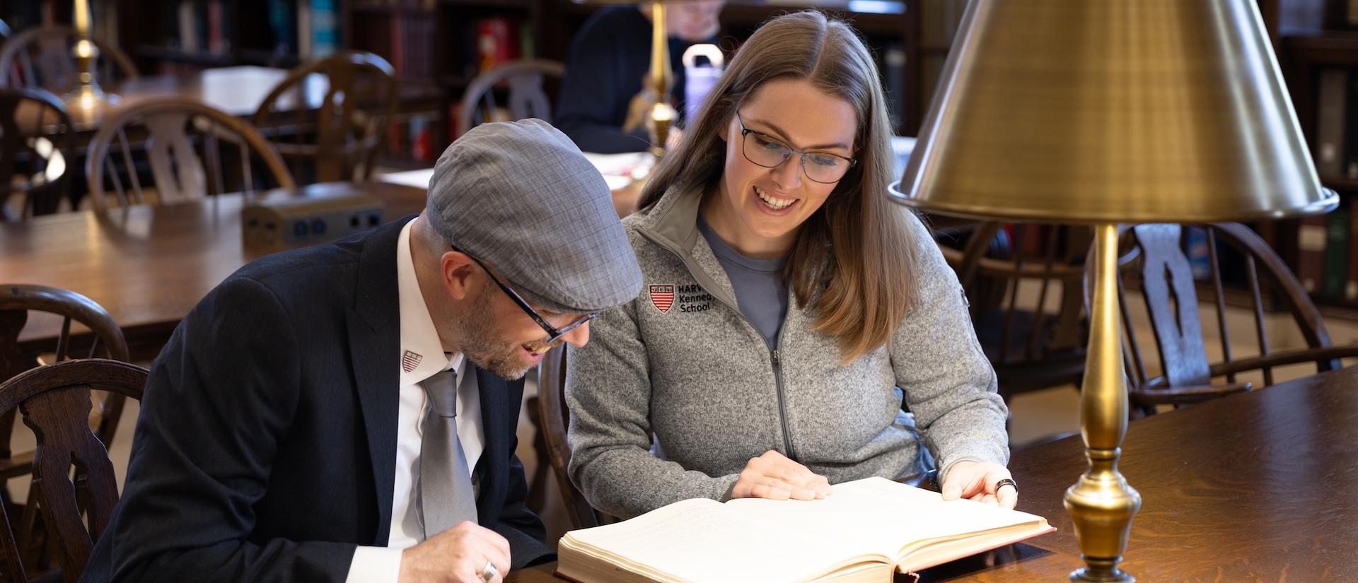 Two people read a large book together.
