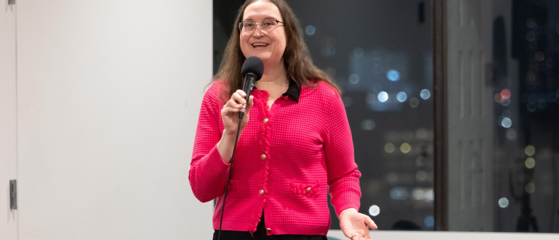 A woman speaks enthusiastically into a microphone.